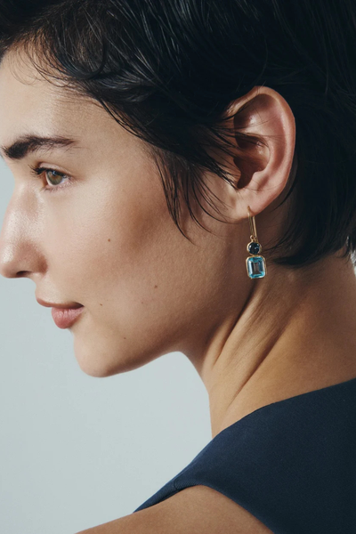 Close-up lifestyle portrait of a model wearing the Temple of the Sun Aqua Drop Earring in 18k Gold Vermeil set with dual blue topaz gemstones.