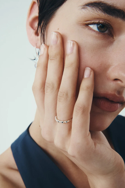 Profile photo of a model resting her hand on her cheek, displaying the Temple of the Sun Aqua Ring in Sterling Silver with blue topaz accents.