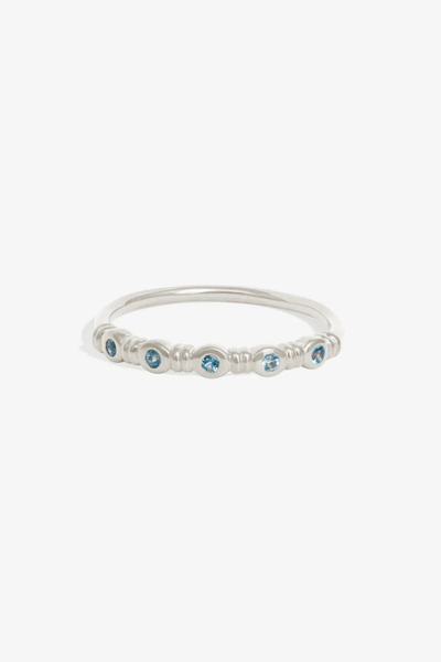 Studio product shot of the Temple of the Sun Aqua Ring in polished Sterling Silver set with five round teal topaz stones against a white background.