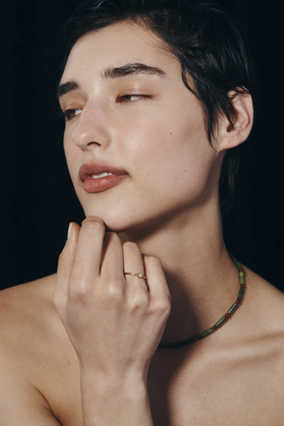 Editorial lifestyle photo of a model resting her chin on her hand while wearing the Temple of the Sun Bia Ring in 18k Gold Vermeil.