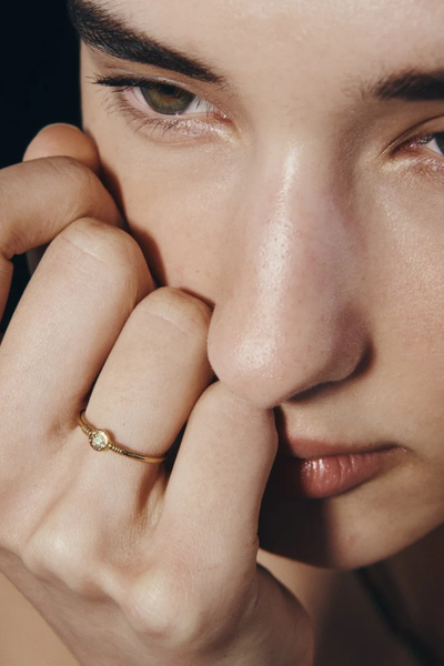 Extreme macro close-up of a model's hand on her face, highlighting the detail of the Temple of the Sun Bia Ring in 18k Gold Vermeil.