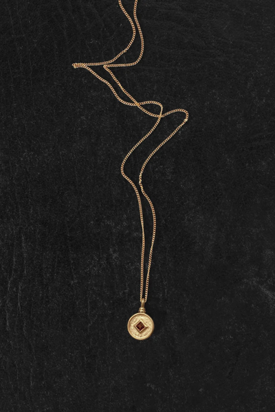 Detailed overhead shot of the Temple of the Sun Blaze Coin pendant in 18k Gold Vermeil highlighting the princess-cut orange garnet gemstone and brushed texture.
