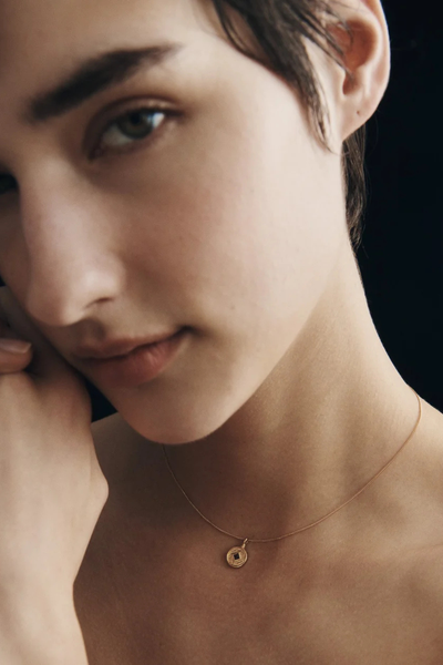 Close-up lifestyle portrait of a model wearing the Temple of the Sun Blaze Coin Necklace in 18k Gold Vermeil.