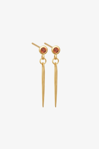 Studio product shot of a pair of Temple of the Sun Cinder Earrings in 18k Gold Vermeil featuring orange garnet stud posts and tapered spike drops on a white background.