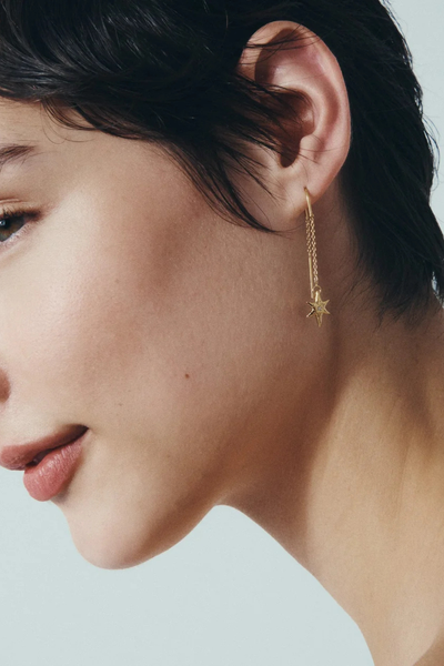 Profile view of a model wearing a Temple of the Sun Electra Threader Earring in 18k Gold Vermeil, highlighting the star charm drop.