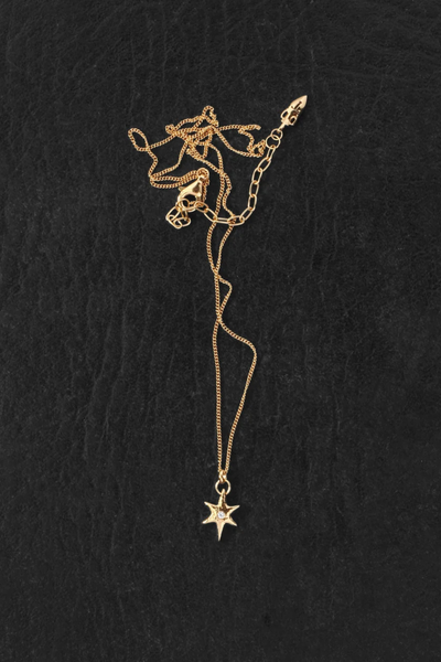 Overhead flat-lay shot of the Temple of the Sun Electra Necklace in 18k Gold Vermeil displayed on a dark textured surface, showing the chain clasp and star charm.