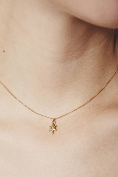 Close-up shot of a model wearing the Temple of the Sun Electra Gold Vermeil Star Necklace resting near the collarbone.