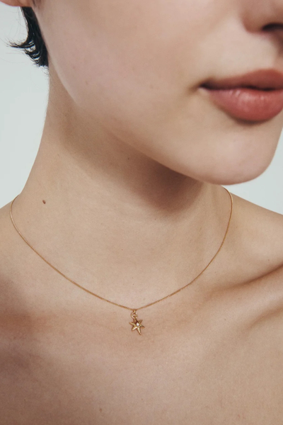 Lifestyle portrait of a model wearing the Temple of the Sun Electra Star Pendant Necklace in 18k Gold Vermeil.