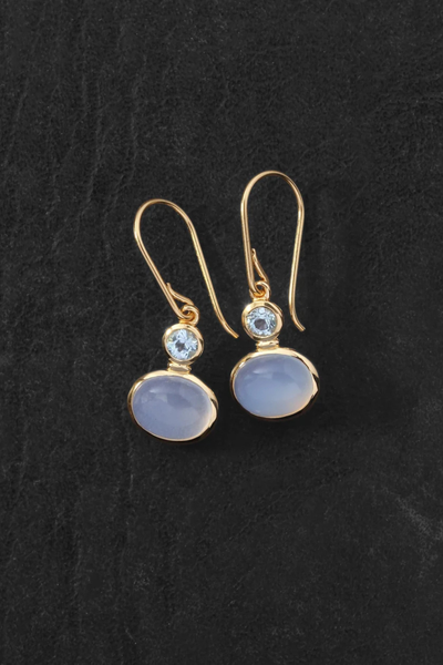 Flat-lay shot of the pair of Temple of the Sun Ether Earrings in 18k Gold Vermeil laid out on a dark textured surface.