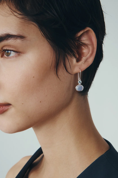 Close-up lifestyle view of a model wearing the Temple of the Sun Ether Earring in Sterling Silver resting her hand on her chin.