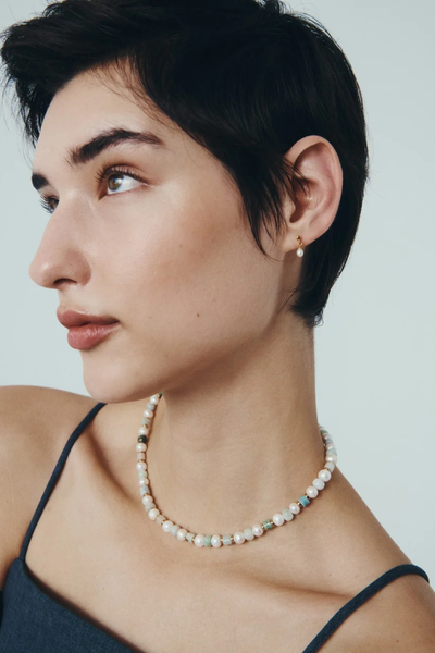 Profile view of a model wearing the Hydra Necklace paired with delicate pearl drop earrings.