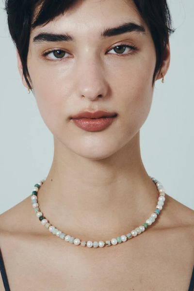 Frontal portrait of a model showcasing the fit of the Hydra Necklace against a neutral background.