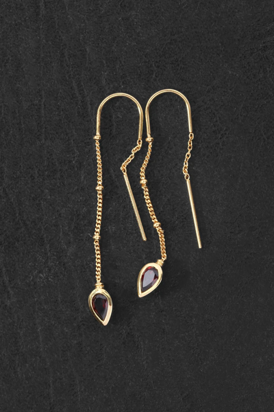 Overhead flat-lay view of the pair of Temple of the Sun Ignis Threader Earrings in 18k Gold Vermeil laid out on a dark slate surface.