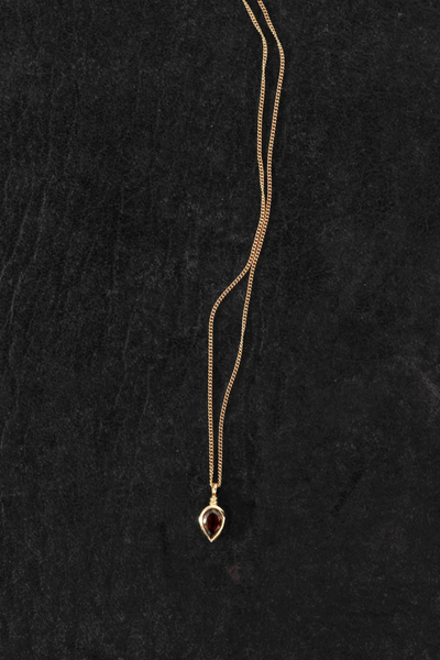 Flat-lay product photo of the Temple of the Sun Ignis Necklace in 18k Gold Vermeil on a dark textured surface.