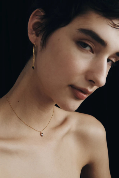 Direct view of a model wearing the gold Ignis pendant necklace from the Temple of the Sun IGNIS collection.