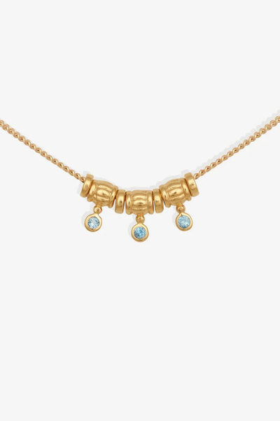 Extreme close-up studio shot of the central station beads and bezel-set London Blue Topaz charms of the Isla Necklace.