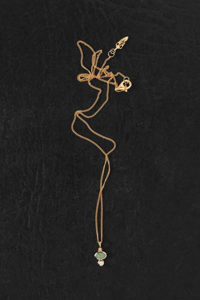 Flat-lay product shot of the Temple of the Sun Ma Necklace in 18k Gold Vermeil laid out on a dark textured surface, showing the chain clasp and pendant.