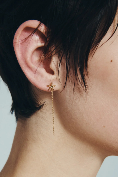 Close-up profile view showing the star stud and fine chain drop of the Temple of the Sun Seba Stud Earring on a model.