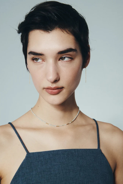 Frontal portrait photo of a model showcasing the delicate hanging chains of the Seba Stud Earrings in 18k Gold Vermeil.