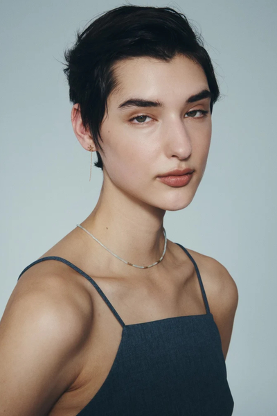 Angled portrait shot of a model wearing the Temple of the Sun Seba Stud Earrings in 18k Gold Vermeil paired with a fine beaded necklace.