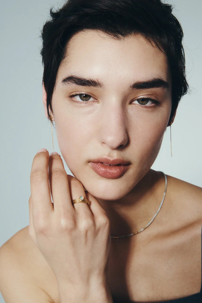 Close-up lifestyle photo of a model wearing the Temple of the Sun Seba Stud Earrings in 18k Gold Vermeil with a hand resting on her chin.