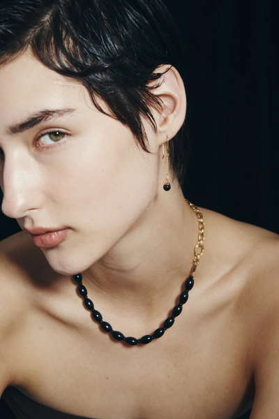 Side view of a model wearing the Temple of the Sun Sela Earring in 18k Gold Vermeil paired with a matching black onyx chain necklace.