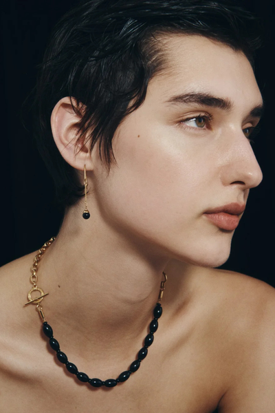 Three-quarter portrait of a model showcasing the Sela Earring in 18k Gold Vermeil and black onyx bead drop.