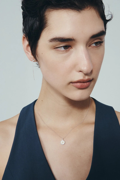 Direct studio portrait of a model wearing the Temple of the Sun Soma Coin Necklace in Sterling Silver paired with fine drop star earrings.