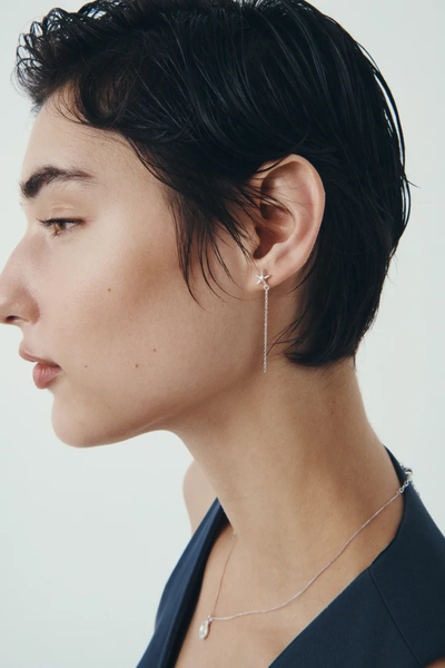 Close-up profile photo of a model highlighting the delicate silver chain and pendant along with the Seba star drop earring.