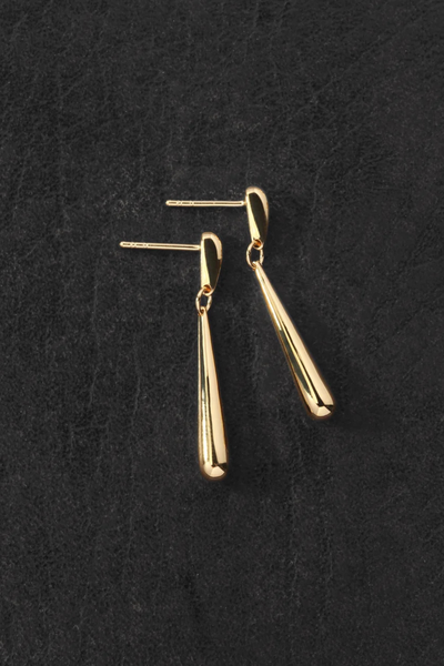 Flat-lay product shot of the Temple of the Sun Stilla Earrings in 18k Gold Vermeil resting on a dark textured background.