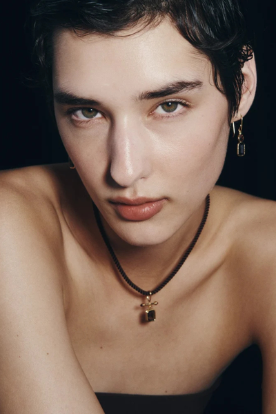 Frontal portrait photo of a model displaying the Umber drop earrings with garnet and smoky quartz stones.