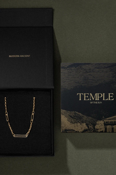 Top-down view of an open black Temple of the Sun branded gift box beside an artwork card on a dark green background.