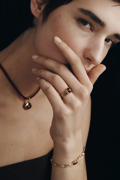 Close-up model shot showcasing the Vega Garnet Ring worn on the ring finger.