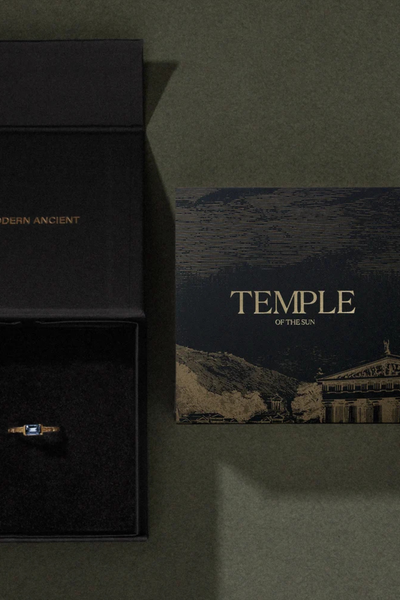 Top-down view of an open black Temple of the Sun gift box alongside a brand artwork card.