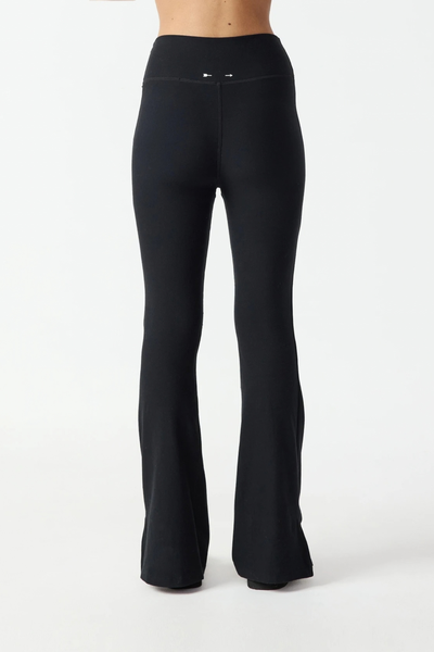 Full-length studio rear view of a model wearing the black flare pants, showing the full length and flare silhouette from behind.