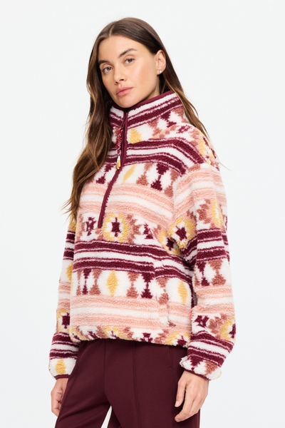 Three-quarter side angle of a model wearing the Harlow Fleece Pullover. This view highlights the plush, recycled faux shearling jacquard texture, elasticated wrists, and functional zippered pockets.