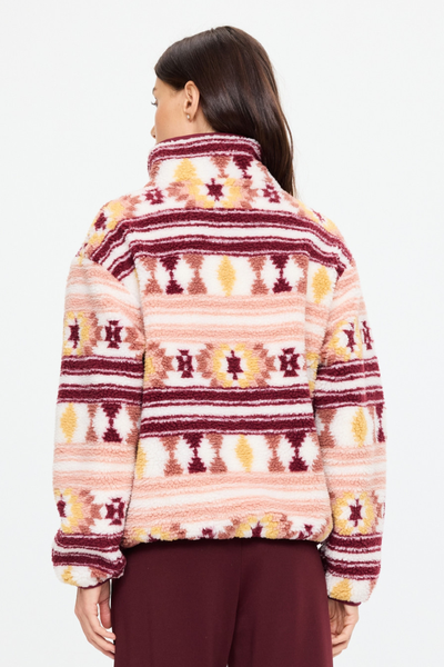 Rear studio view of a model wearing the Harlow Fleece Pullover, showcasing the seamless continuation of the Aztec pattern across the back and sleeves, and the comfortable drape of the recycled fleece.