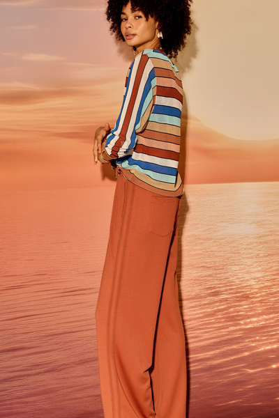 Three-quarter studio view of model posing with her hand in her pocket wearing The Upside Iza Milla Long Sleeve Knit Top in Stripe.
