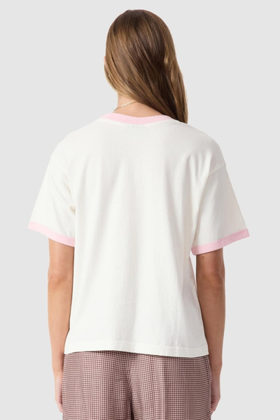 Studio rear view of a model wearing the quartz organic cotton t-shirt with pink contrast trim and patterned trousers.