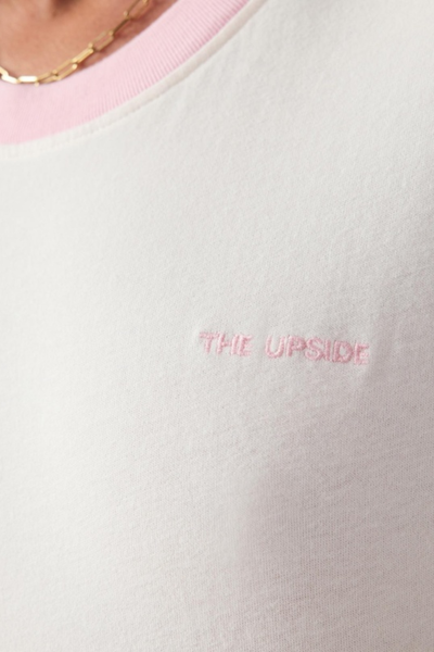 Close-up studio shot highlighting the embroidered pink "The Upside" brand logo on the chest of the quartz tee.