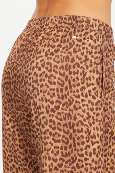 Close-up studio detail shot of the back of the Javan Juliet Pant, showcasing the elasticated waistband and the signature cream embroidered arrow logo of The Upside positioned on the upper right hip over the leopard print twill.
