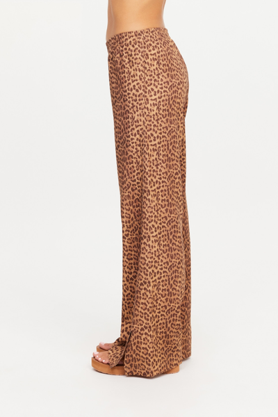 Side profile studio shot of a model wearing the Javan Juliet Pant. This angle highlights the clean drape of the slinky, lightweight twill leopard print fabric and the split detail at the outer ankle hem.