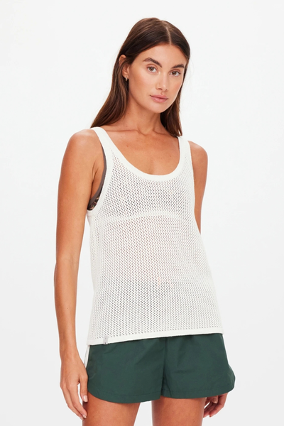 Front-facing studio view of a model wearing the cream open-knit tank top paired with dark green athletic shorts.
