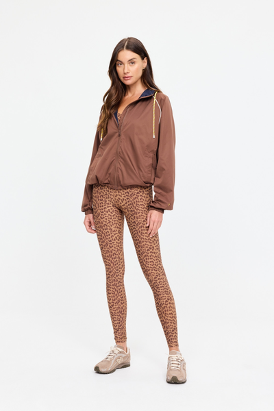 Full-length studio shot of a model wearing the chocolate brown Lila Zip Through Jacket, styled with animal print leggings and neutral athletic sneakers. The image highlights the jacket's regular fit and casual silhouette.