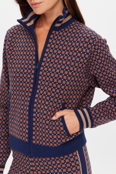 A mid-shot studio portrait focusing on the front closure of the semi-zipped geometric star jacquard knit jacket, detailing the tonal navy zipper track and the fine knit fabrication texture.