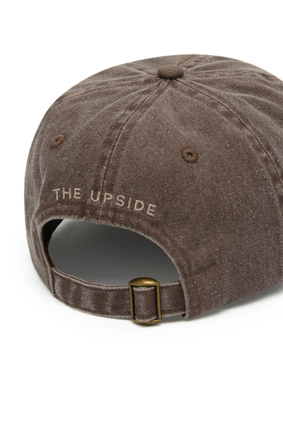 Close-up studio view of the back of the washed brown soft cotton cap, highlighting the adjustable strap with a bronze metal slider buckle and the embroidered "The Upside" logo above the opening.