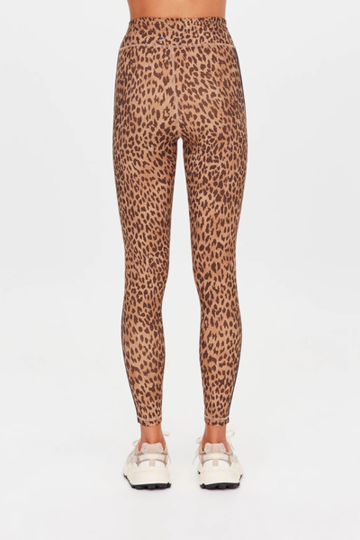 Studio side profile view from the waist down of activewear leopard print midi leggings highlighting the dual navy side seam binding stripes.
