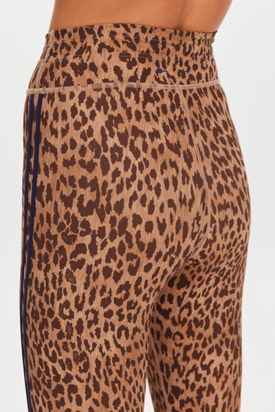 Studio rear view from the waist down of a model wearing leopard print 25-inch midi leggings with ankle-length fit and sneakers.
