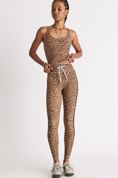 Full-length studio front shot of a model wearing a scoop neck leopard print activewear tank top and matching high-waisted midi leggings with side navy stripes and a light blue drawstring.