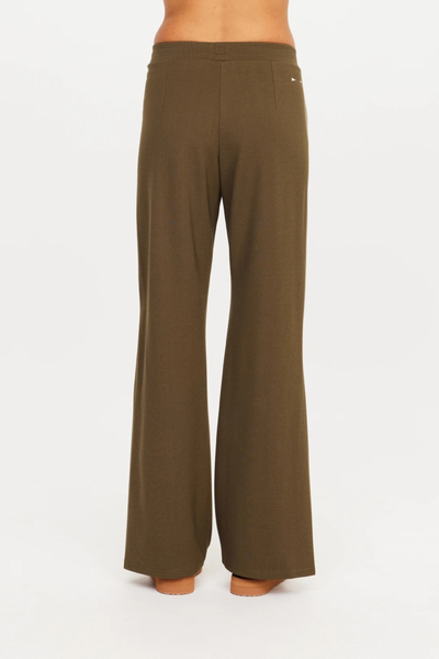 Back view of a model wearing The Upside Petra Flare Pant in Olive, showcasing the wide flare leg cut and elasticated high waistband fit.